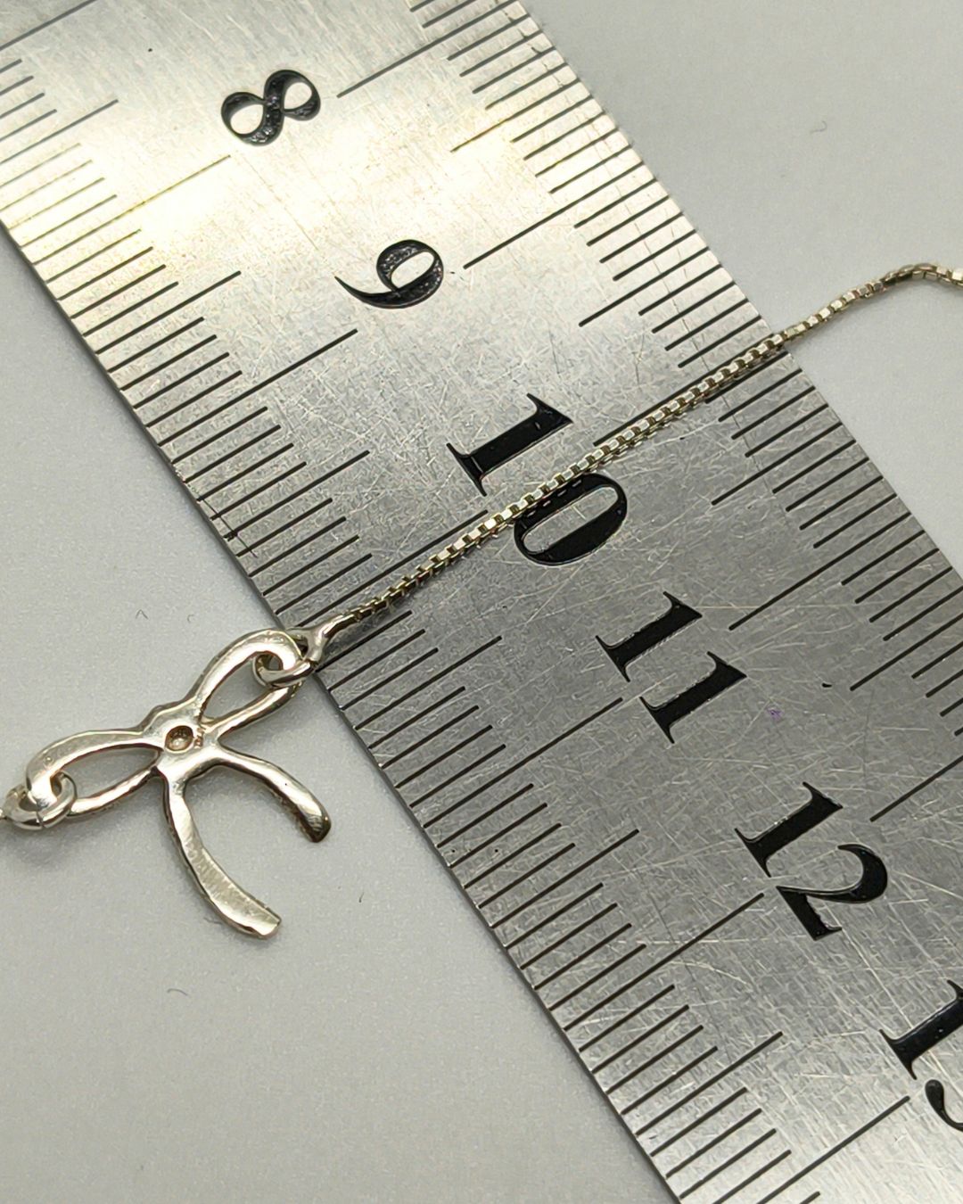 Collar de plata 925 con moño vista posterior y sobre regla para contexto de medida Collar de plata 925 con moño vista posterior y sobre regla para contexto de medida