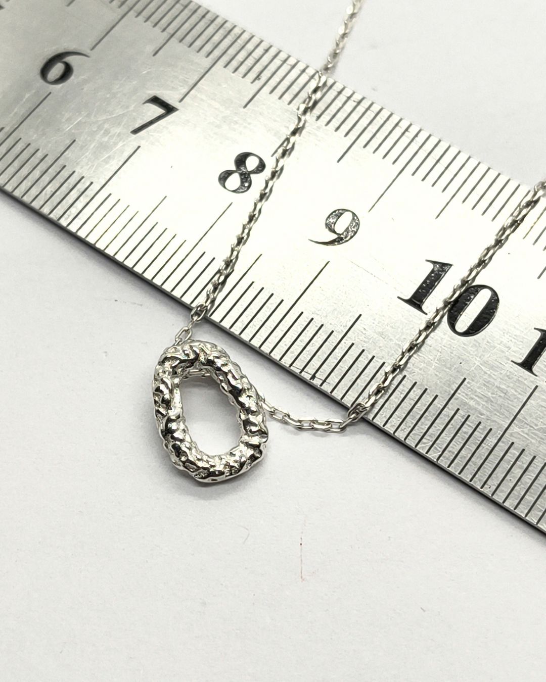 Collar de plata 925 con pasante ovalo martillado sobre regla para contexto de medida Collar de plata 925 con pasante ovalo martillado vista sobre regla para contexto de medida
