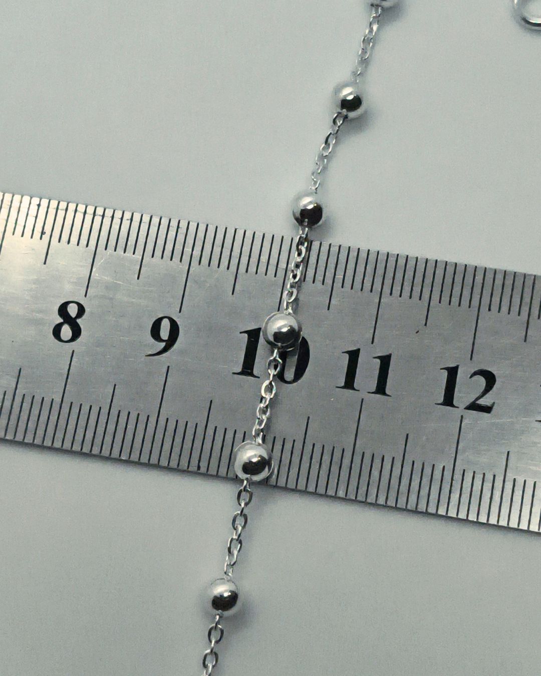 Pulsera de plata 925 denario con cuentas de 4mm y cruz y regulación en el extremo sobre regla para contexto de medida Pulsera de plata 925 denario con cuentas de 4mm y cruz y regulación en el extremo sobre regla para contexto de medida
