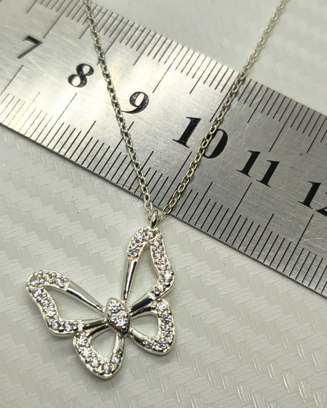 Collar de plata 925 con mariposa calada y circonias engarzadas sobre regla para contexto de medida Collar de plata 925 con mariposa calada y circonias engarzadas sobre regla para contexto de medida