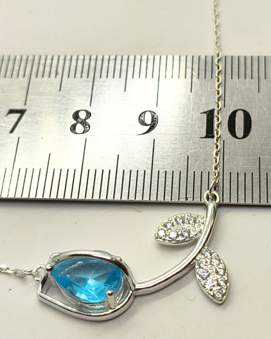 Collar de plata con centro de tulipan apaisado con circonias blancas y de color sobre regla para contexto de medida Collar de plata con centro de tulipan apaisado con circonias blancas y de color sobre regla para contexto de medida