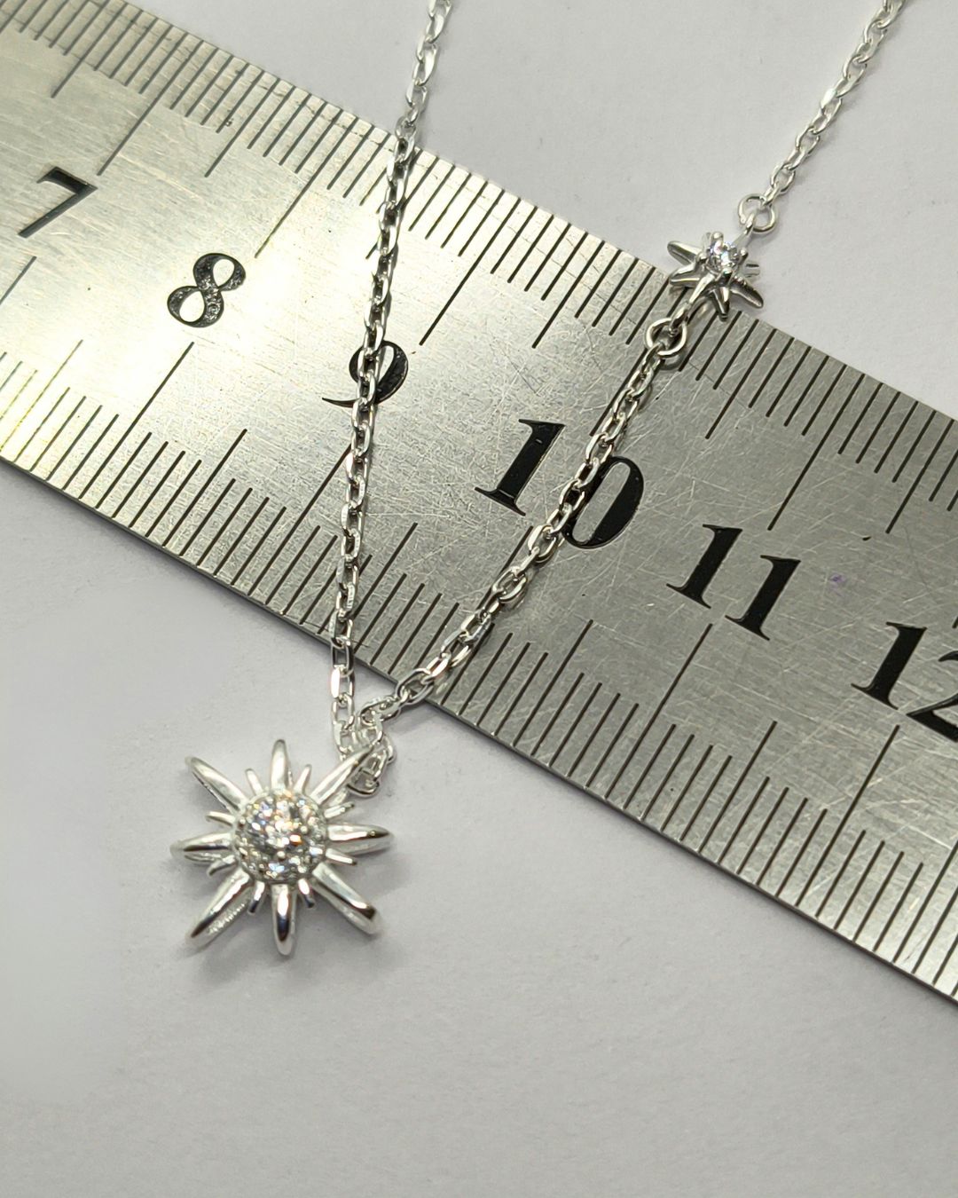 Collar de plata 925 con dije pasante de lucero y uno fijo sobre regla para contexto de medida Collar de plata 925 con dije pasante de lucero y uno fijo sobre regla para contexto de medida
