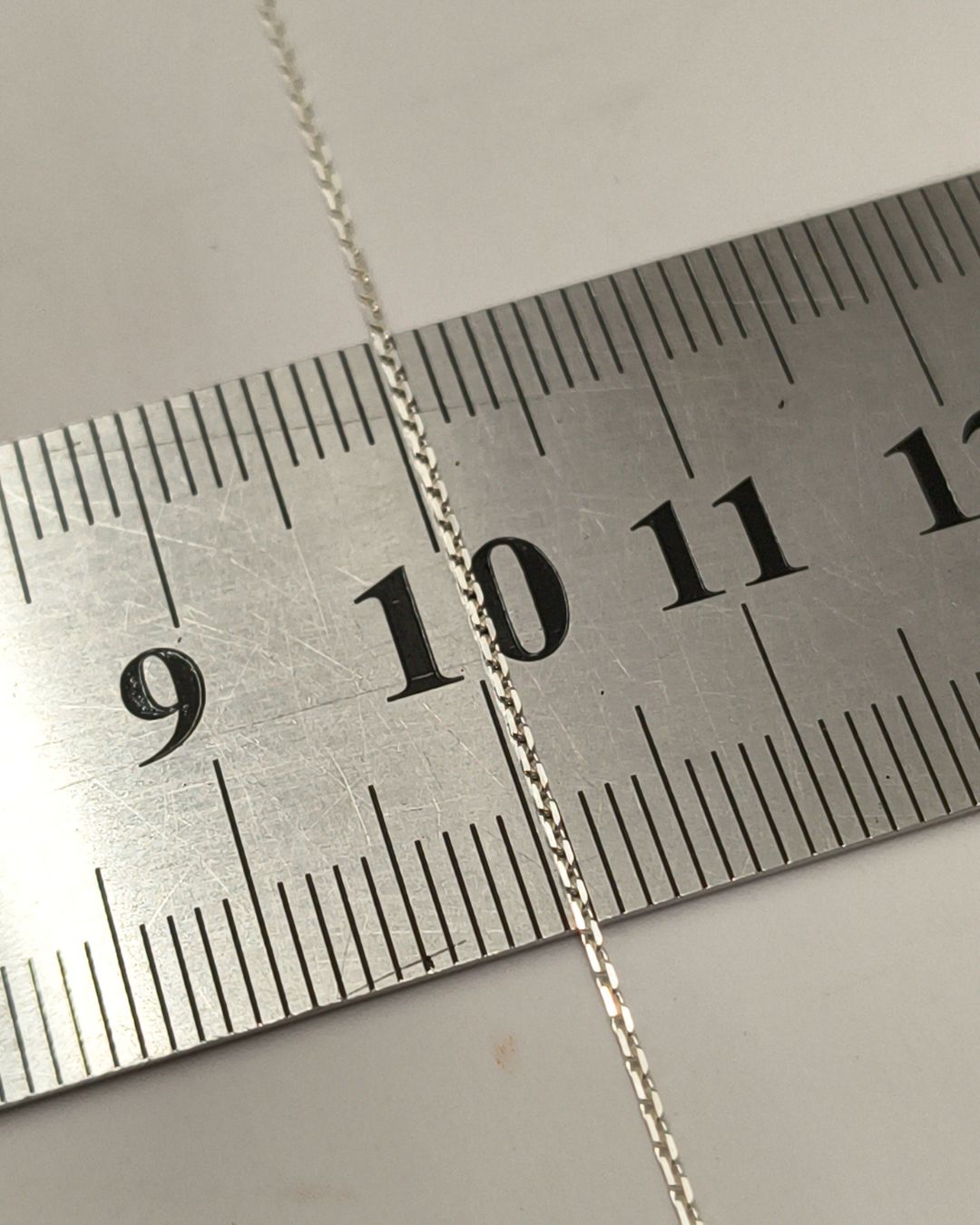 Collar de plata 925 con inicial pasante sobre regla para contexto de medida Collar de plata 925 con inicial pasante sobre regla para contexto de medida