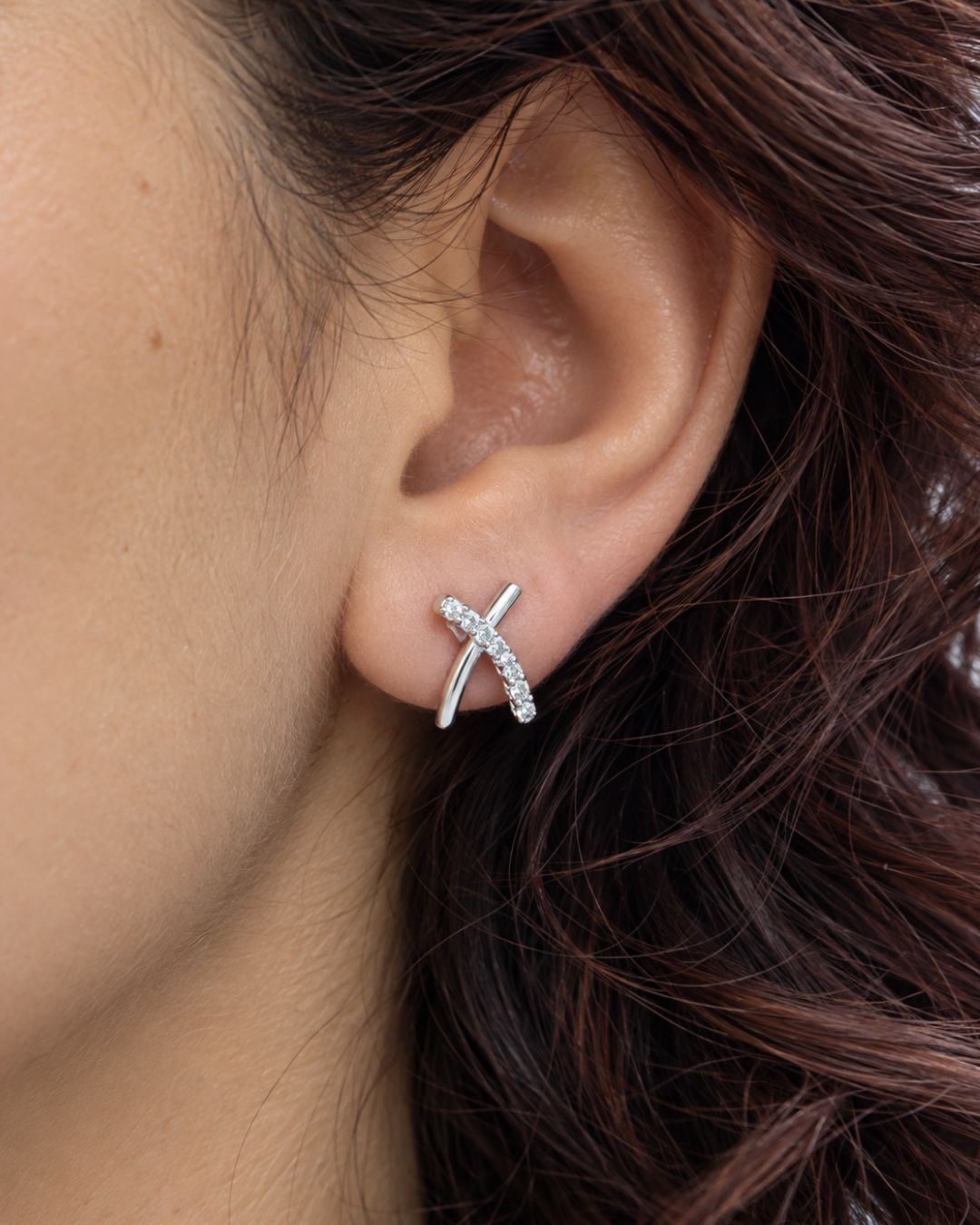 Aros de plata 925 y circonias en forma de equis colocados en oreja Aros de plata 925 y circonias en forma de equis colocados en oreja