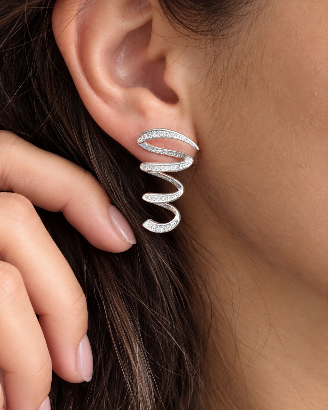 Aros de plata 925 con circonias en forma de espiral aplanado colocados en oreja Aros de plata 925 con circonias en forma de espiral aplanado colocados en oreja