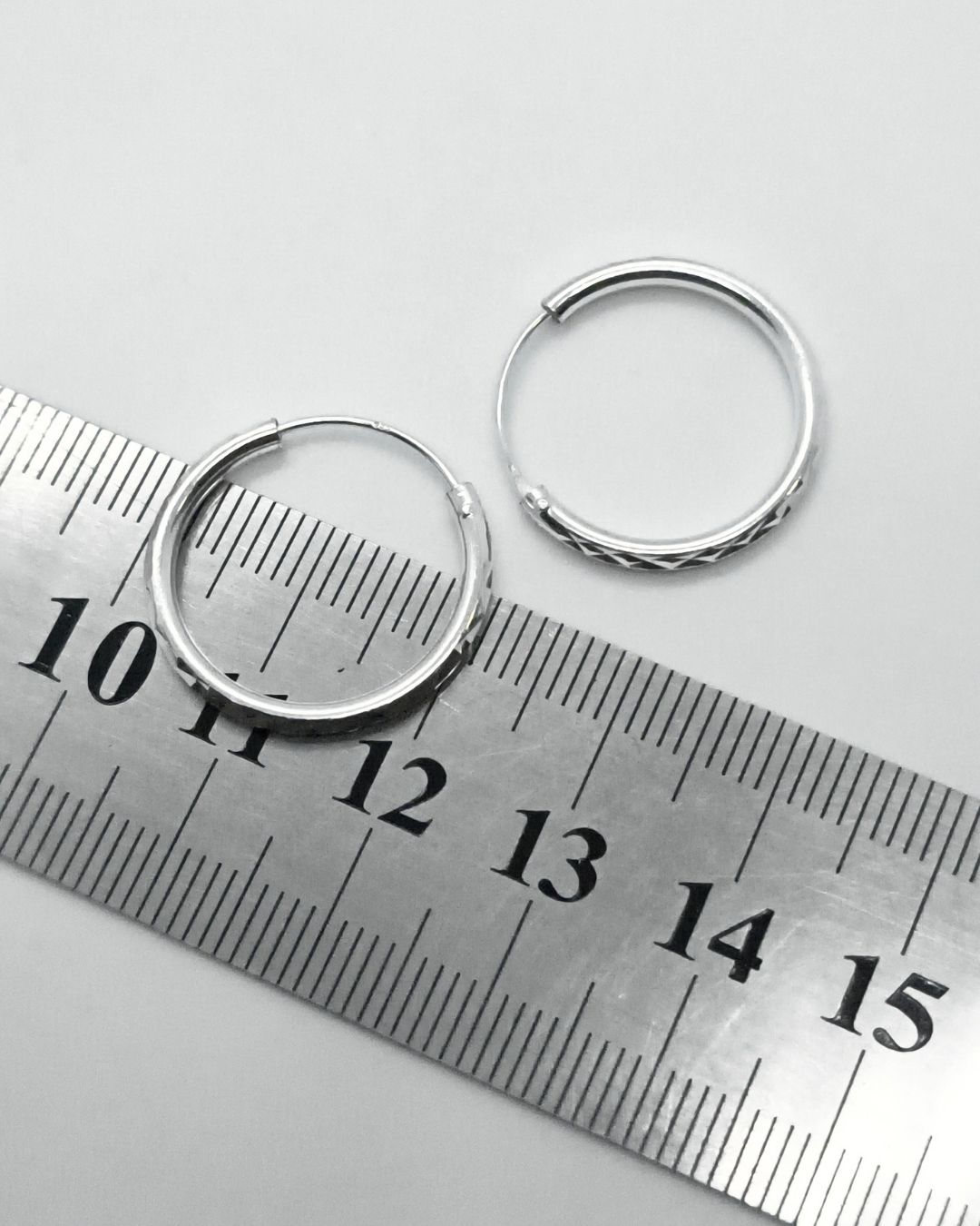 Aros de plata 925 argollas facetadas de 20mm. sobre regla para contexto de medida Aros de plata 925 argollas facetadas de 20mm. sobre regla para contexto de medida