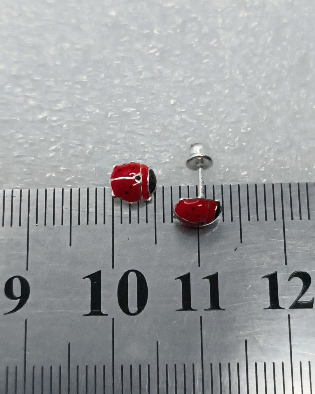 Aros abridores de plata 925 de vaquita de san antonio sobre regla para contexto de medida Aros abridores de plata 925 de vaquita de san antonio sobre regla para contexto de medida